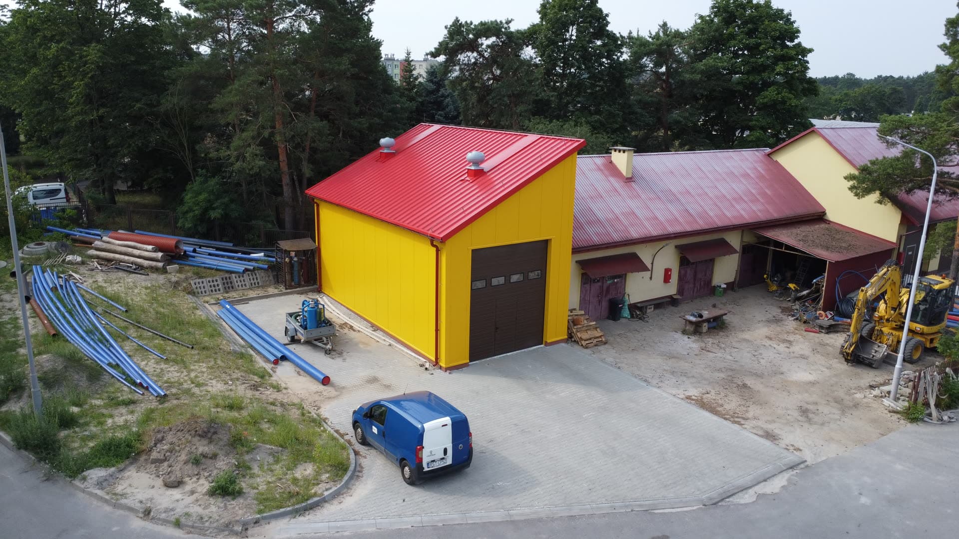 Hala stalowa z czerwonym dachem dwuspadowym, szerokie ujęcie z drona