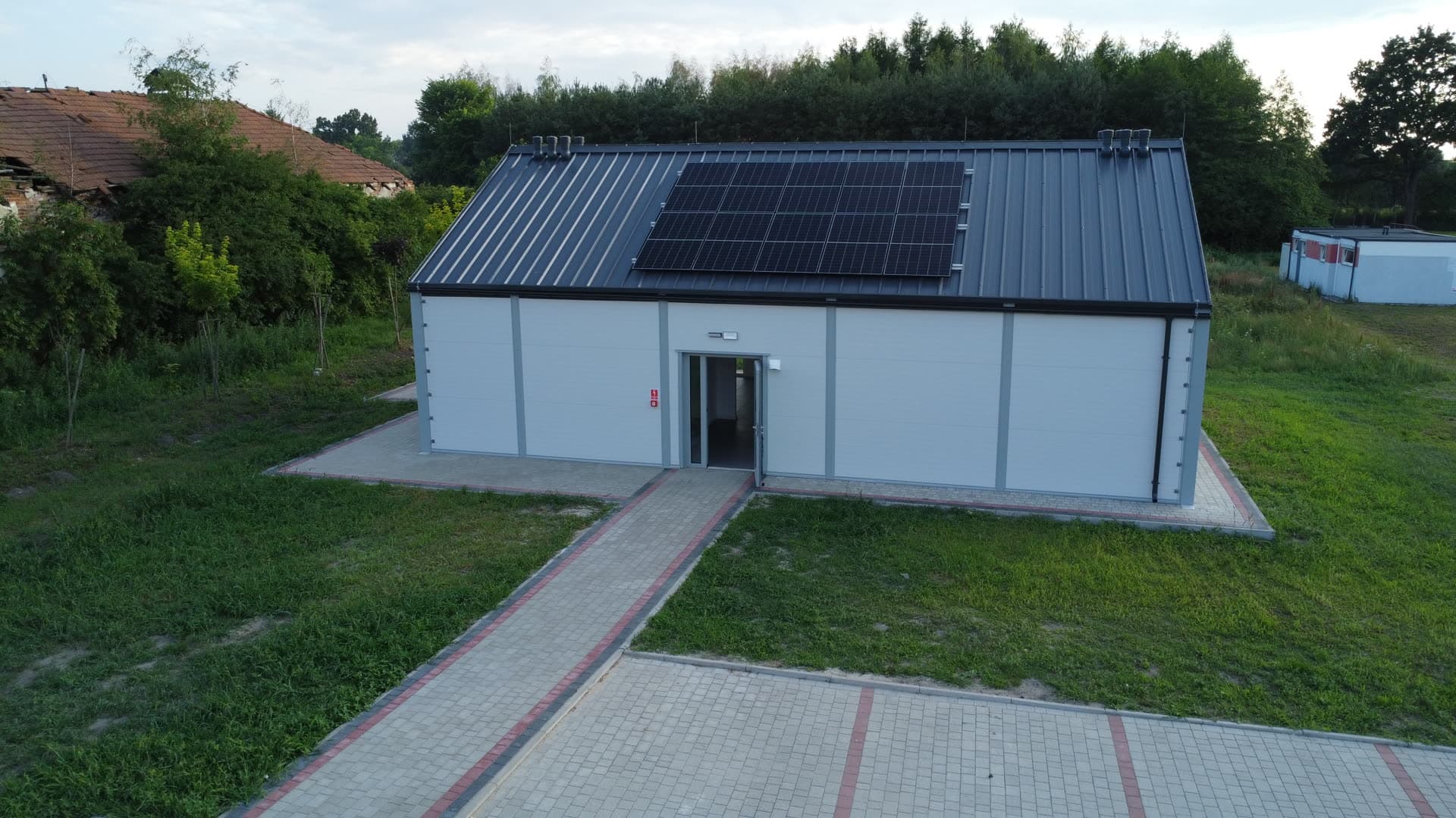 Symetryczna elewacja frontowa hali z centralnym chodnikiem